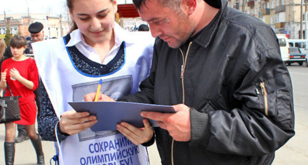 Флеш-моб за сохранение борьбы как олимпийского вида спорта прошел возле кинотеатра "Дружба". На снимке: волонтер собирает подписи. Владикавказ, 15 марта 2013 г. Фото Эммы Марзоевой для "Кавказского узла"