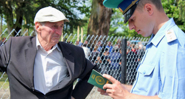 Пункт пропуска пешеходов через границу с Грузией открылся в двух селах Гальского района. На снимке: пограничник проверяет абхазский паспорт жителя села Отобая. Абхазия, 15 мая 2013 г. Фото Анжелы Кучуберия для "Кавказского узла"