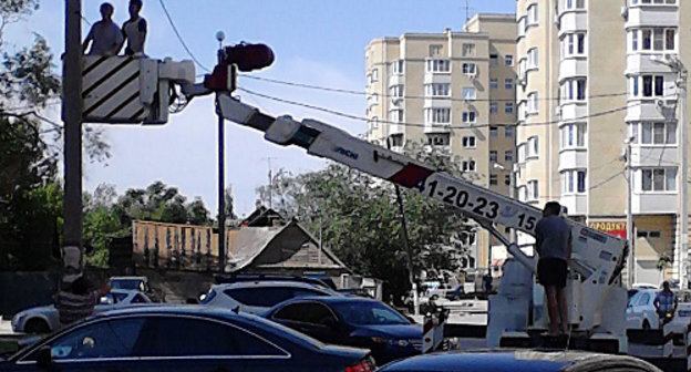 Люди в униформе отрезают силовой кабель, обеспечивавший электричеством дом Порфирьевых на улице Амурской, 14. Астрахань, 6 июня 2013 г. Фото Елены Гребенюк для "Кавказского узла"