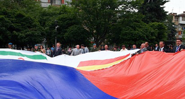 Участники автопробега "Эстафета Флага России" держат государственный флаг с пришитым к нему флагом Северной Осетии. Владикавказ, 10 июня 2013 г. Фото: http://region15.ru