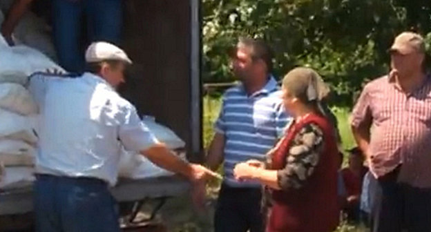 Волонтеры фонда "Чистое сердце" распределяют гуманитарную помощь среди семей храхубинцев, переехавших в Дагестан. Селение Новоаул, Магарамкентский район, 7 июля 2013 г. Кадр из видеорепортажа студии "Шарвили" телеканала ОТВ