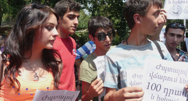 Участники шествия против повышения стоимости проезда на общественном транспорте держат листовки с надписью "Улыбаемся и платим 100 драмов". Ереван, 24 июля 2013 г. Фото Армине Мартиросян для "Кавказского узла"