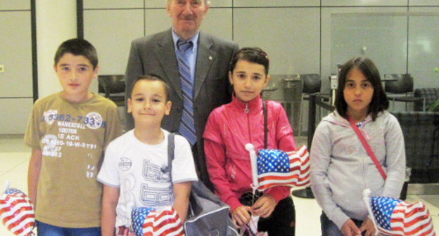 Алихан Ахильгов, руководитель неправительственной общественной организации "Фонд помощи ранее депортированным народам", с детьми из семей беженцев Ингушетии и Чеченской Республики в аэропорту Кеннеди. США, Нью-Йорк, 21 июля 2013 г. Фото предоставлено сотрудником неправительственной организации "Международный институт жизни" Линдой Редфилд