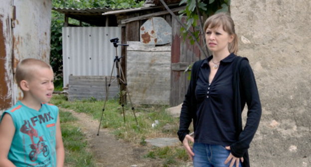 Юлия Салтыкова с сыном, жильцы дома №5-а по улице Акаций, у подсобных строений, которые должны быть снесены по требованию судебных приставов. Сочи, Адлерский район, 8 июня 2013 г. Фоторепортаж Светланы Кравченко для "Кавказского узла"