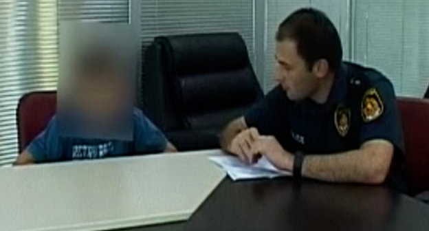 Офицер подразделения полиции района Исани-Самгори беседует с подростком 2001 года рождения , автором звонка о бомбе в тбилисском аэропорту. Тбилиси, 12 сентября 2013 г. Кадр  видеосъемки пресс-службы МВД Грузии, http://police.ge