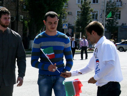 Представитель партии "Единая Россия" раздает флажки с триколором чеченского флага на праздновании Дня республики. Чечня, Грозный, 6 сентября 2012 г. Фото: chechen.er.ru