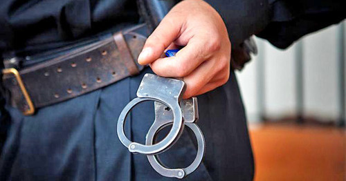 Сотрудник правоохранительных органов с наручниками. Фото: Федор Обмайкин / Югополис Сотрудник правоохранительных органов с наручниками. Фото: Федор Обмайкин / Югополис