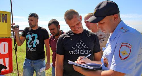 Участники митинга фермеров около трассы "Дон" и сотрудник полиции. 12 августа 2018 года. Фото Вячеслава Прудникова для "Кавказского узла".