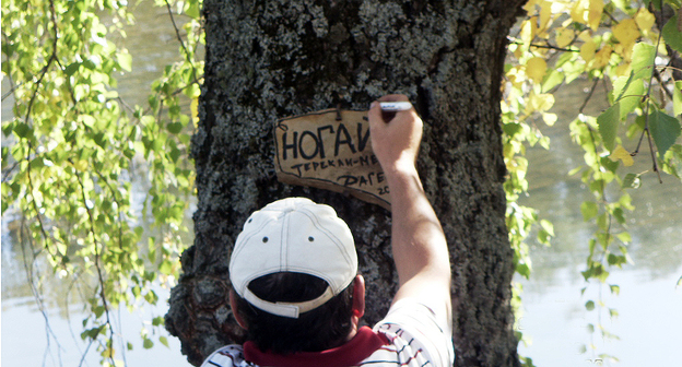 Юноша пишет название посёлка в Ногайском районе. Фото: Ахмат Баетов, http://odnoselchane.ru/?page=photos_of_category&sect=917&com=photogallery