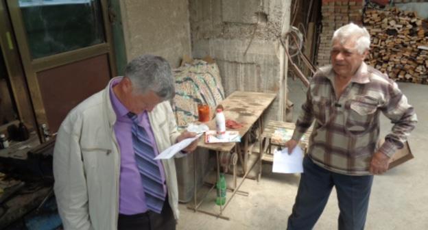 Петр Карпюк (справа) и его сосед читают повестку в суд. Фото Светлана Кравченко для "Кавказского узла".