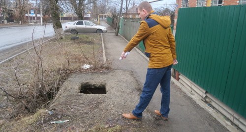 Житель Шахт показывает открытый на дороге люк. Фото Вячеслава Прудникова для "Кавказского узла",