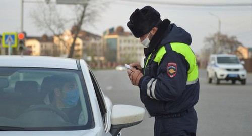 Сотрудник силовых структур проверяет документы у водителя автомобиля. Чечня, апрель 2020 года. Фото: REUTERS/Ramzan Musaev