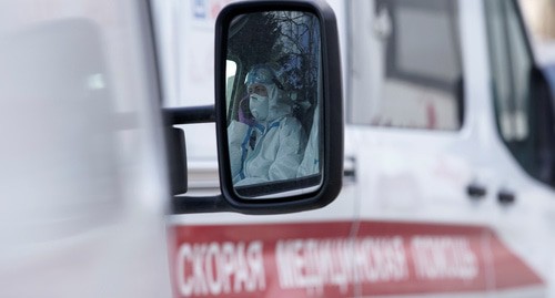 Медицинский работник отражается в зеркале машины скорой помощи. Фото: REUTERS/Tatyana Makeyeva