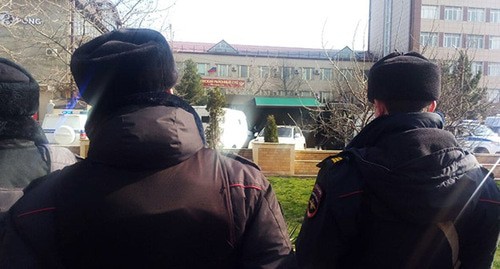 Сотрудники полиции наблюдают за тем, как машину с Ибрагимом Гаджиевым накрывают тентом. 2 апреля 2021 год. Фото Расула Магомедова для "Кавказского узла"