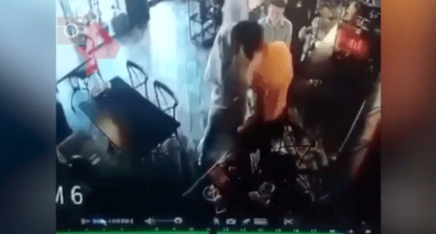 Конфликт между Элезом Мержоевым (в оранжевой одежде) и Айной Гетагазовой (в белом) в назранском кафе 15 июня 2021 года. Стоп-кадр видео https://dni.ru/video/2021/6/17/481045.html