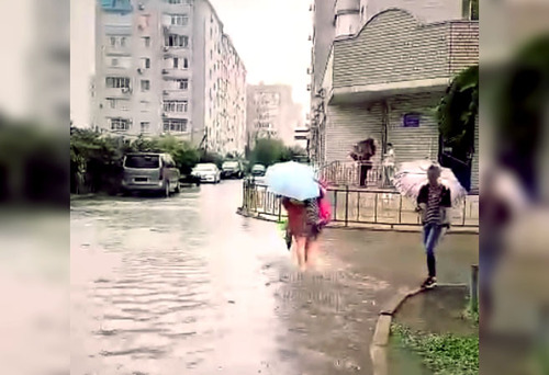 Жительница Краснодара переходит подтопленную улицу. Стоп-кадр из видео на странице https://vk.com/wall-33025155_10315557