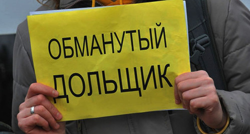Женщина держит в руках плакат: "Обманутый дольщик". Фото: https://riadagestan.ru/news/the_people_s_assembly/edinaya_rossiya_zapustila_onlayn_priemnuyu_dlya_obrashcheniy_obmanutykh_dolshchikov/