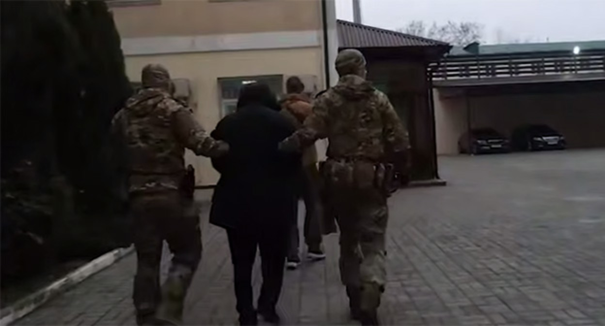 Сотрудники правоохранительных органов сопровождают Изи Алиева. 28 ноября 2025 г. Скриншот видео https://t.me/kommersant/96338