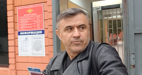Асхабали Алибеков у отдела полиции в Хасавюрте. Сто-кадр видео из YouTube-канала "Дикий десантник" от 11.04.26, https://www.youtube.com/watch?v=D7oP2PtLQkE