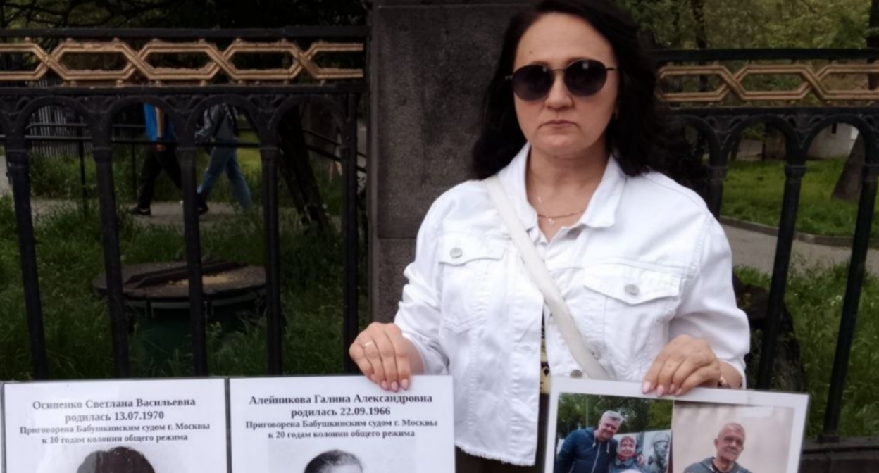 Участница пикета держит в руках плакаты. Скриншот фото RusNews от 02.05.26, https://t.me/rusnews/84132.